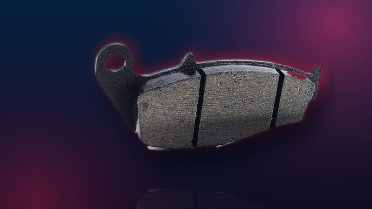 Plaquette de frein à garniture rainurée vue de face sur fond navy dégradé aux reflets rouges — Konipa